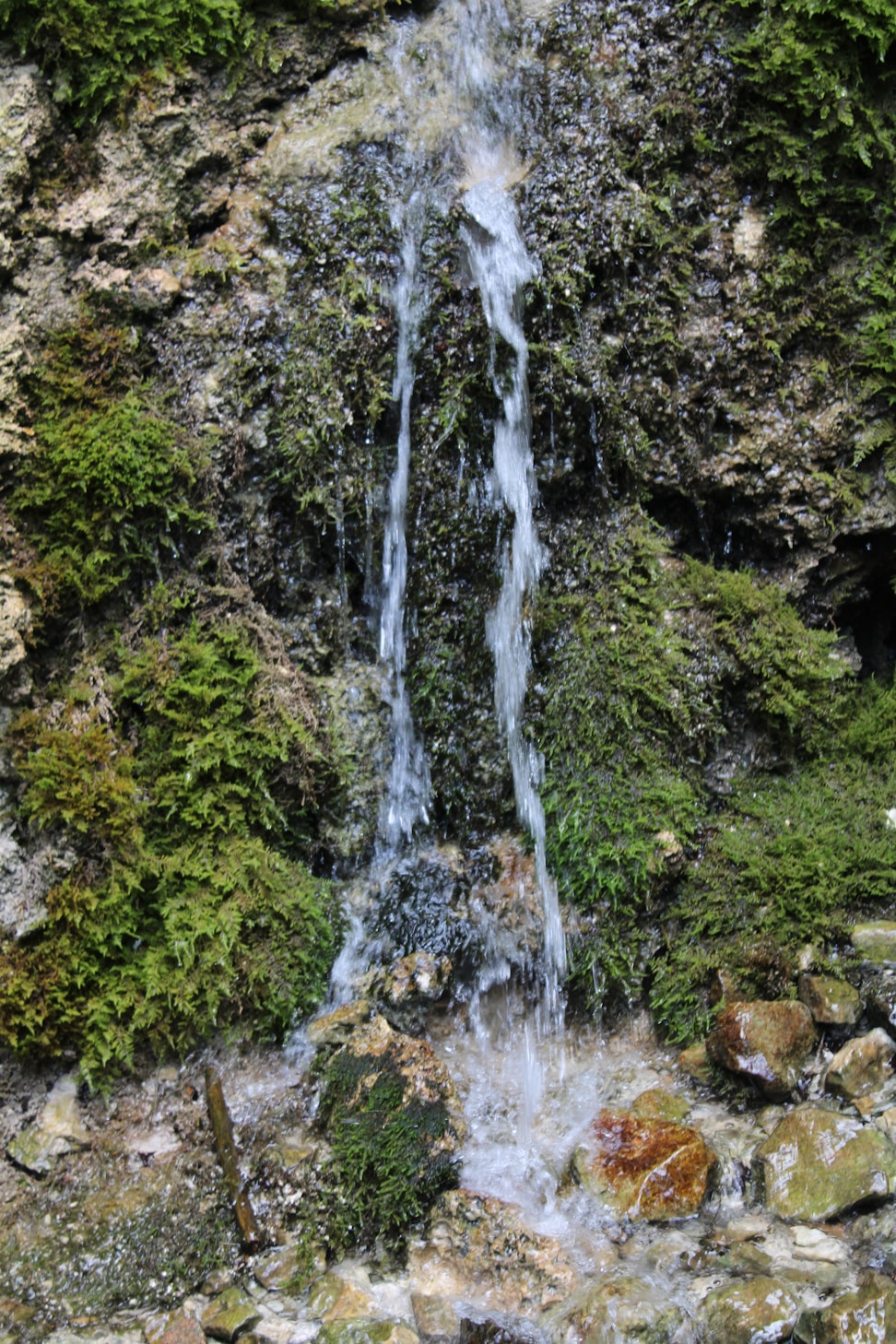 A slender waterfall over moss-covered rock