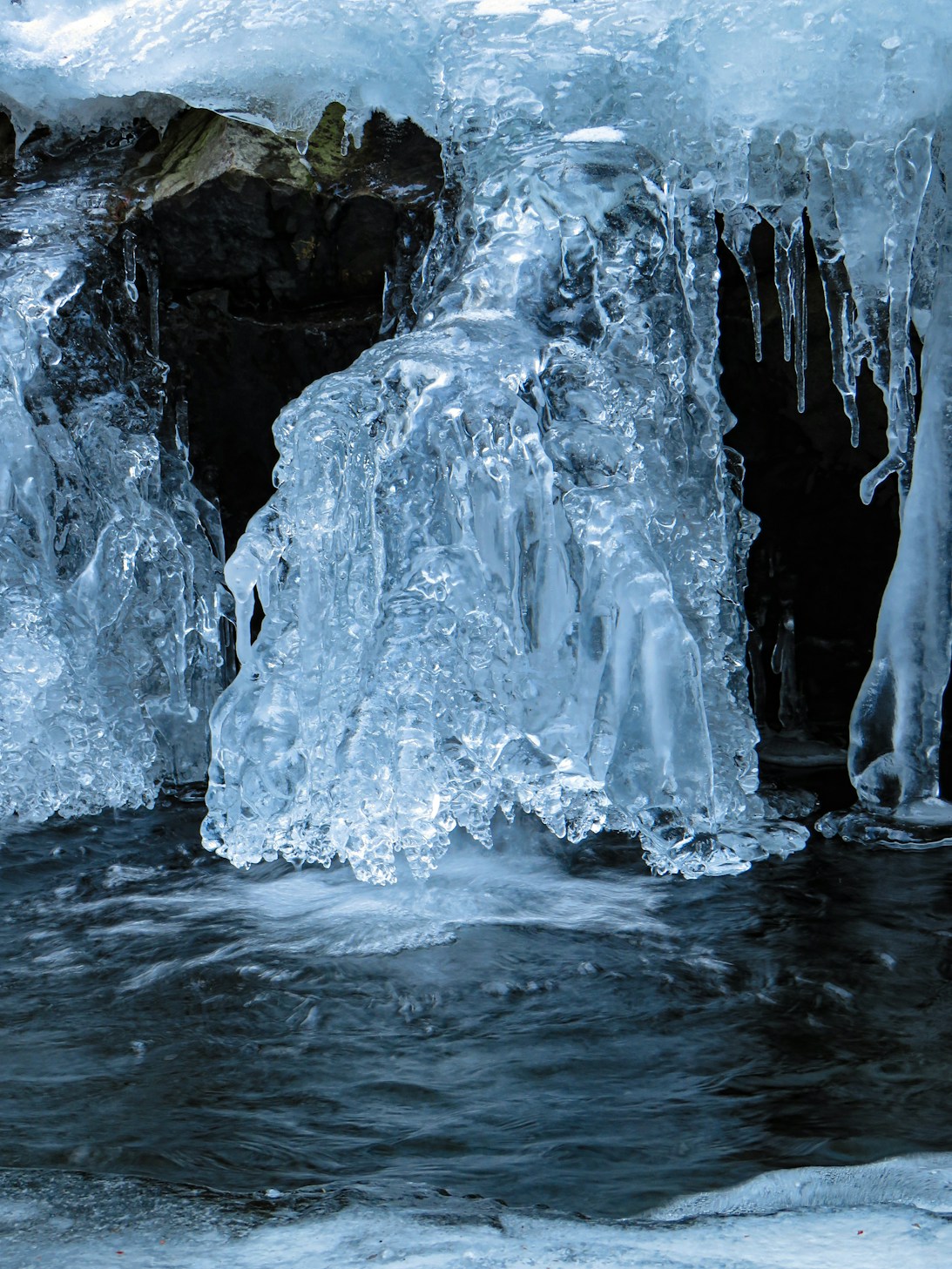 Ice formations above dark flowing water