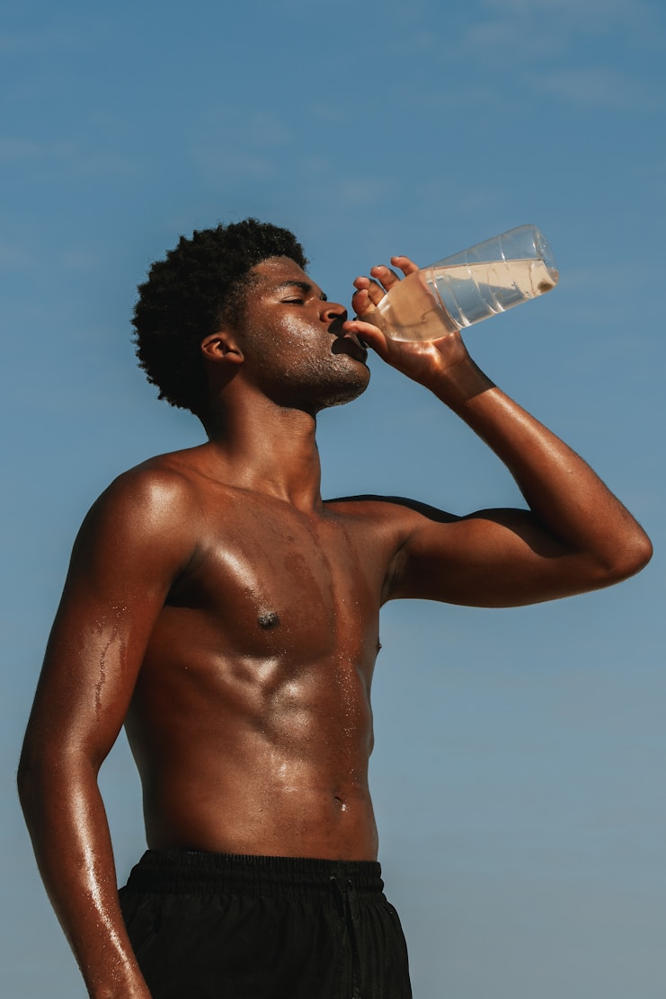 A man drinking water against a blue sky